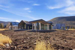 Rear view of house featuring a mountain view, a patio, and a metal roof