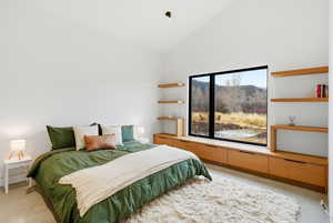 Bedroom featuring light colored carpet, vaulted ceiling, and a mountain view