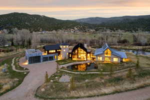 Modern architectural residence featuring multiple buildings, a large pond, and a gravel driveway