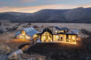 Back of house at dusk featuring a patio area, a metal roof, a chimney, and a mountain view