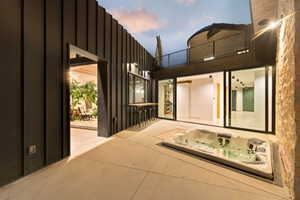 Outdoor patio featuring an integrated spa, concrete hardscaping, and metal siding