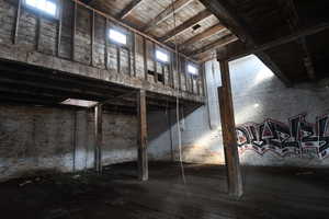 Misc room with brick wall, dark wood-style flooring, and a high wooden ceiling
