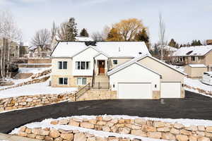 View of front of home with stone siding, an attached garage, asphalt driveway, and a residential view