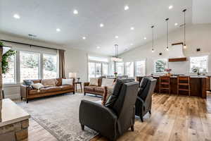 Living area with vaulted ceiling, light wood finished floors, and recessed lighting