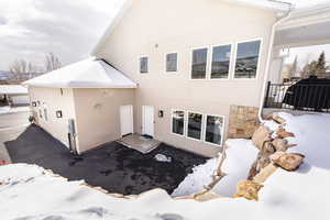 Snow covered property with stucco siding and stone siding