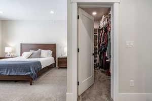 Bedroom with light carpet, a walk in closet, and recessed lighting