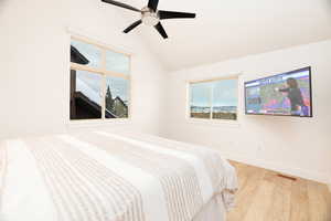 Bedroom featuring light wood finished floors, vaulted ceiling, and a ceiling fan