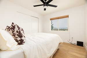 Bedroom featuring light wood-style floors, a closet, and a ceiling fan
