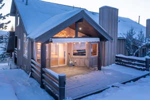 Snow covered property featuring a wooden deck and board and batten siding