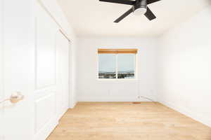 Unfurnished bedroom featuring light wood-style flooring, ceiling fan, and a closet