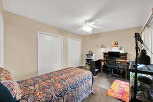 Bedroom with a desk, carpet flooring, multiple closets, and ceiling fan