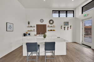 Kitchen with open shelves, white cabinets, a kitchen breakfast bar, light wood-type flooring, and stainless steel microwave