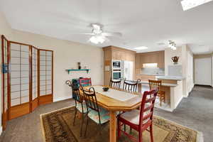 Dining space with light carpet and a ceiling fan