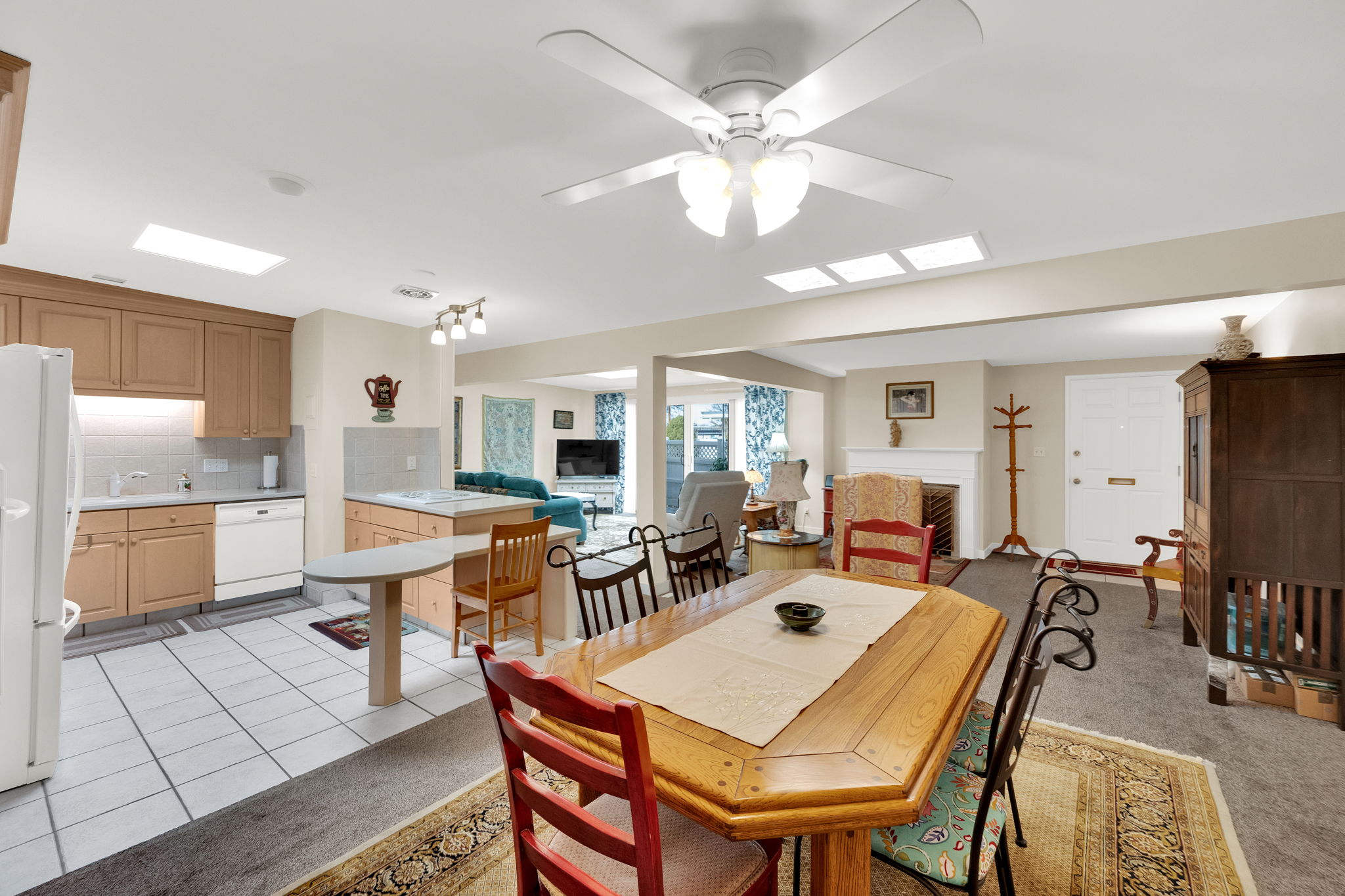 Dining space with a fireplace, a ceiling fan, and light carpet