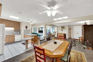 Dining space with a fireplace, a ceiling fan, and light carpet