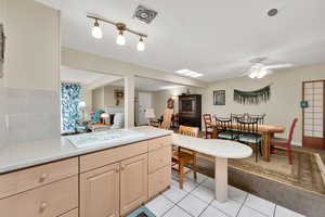 Kitchen with light countertops, light wood finish cabinets, ceiling fan, and light tile patterned flooring