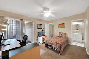 Bedroom featuring an office area, carpet, access to outside, a ceiling fan, and ensuite bath