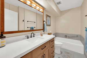 Bathroom featuring vanity, light tile patterned floors, and a garden tub