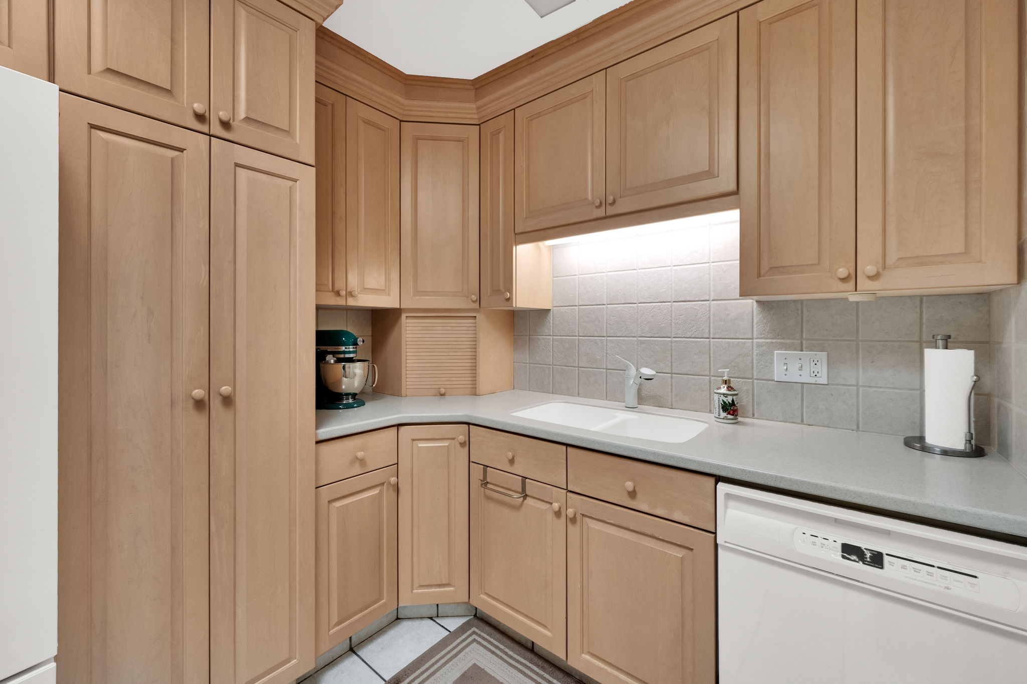 Kitchen with white appliances, light countertops, light tile patterned floors, and backsplash