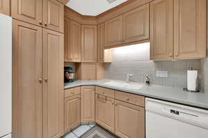 Kitchen with white appliances, light countertops, light tile patterned floors, and backsplash
