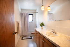 Main floor Bathroom featuring vanity, shower / bath combo with shower curtain, light flooring, and a textured ceiling