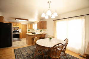 Dining area featuring light wood-style flooring, a chandelier, and a textured ceiling