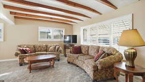 Living room featuring vaulted ceiling with beams and carpet floors