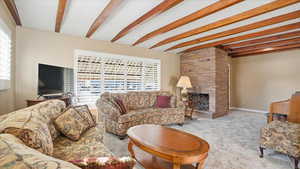 Carpeted living area with a fireplace and beamed ceiling