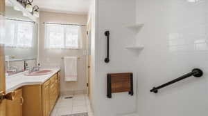 Full bath with vanity, light tile patterned floors, and tiled shower