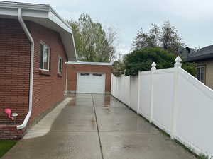 Brick exterior featuring white window trim, white gutters, and a concrete driveway leading to an attached garage with a white overhead door