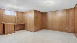Basement featuring light floors and wooden walls