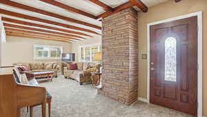 Foyer featuring beam ceiling and carpet