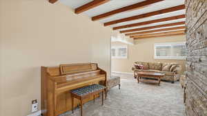 Sitting room with light carpet and beam ceiling