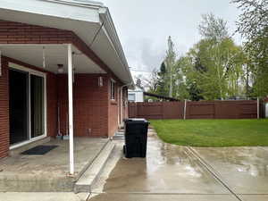 Rear concrete patio featuring a sliding glass door entry, brick exterior, and white soffit