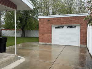 Detached garage with red brick exterior and a white paneled garage door featuring decorative lites