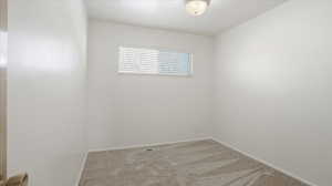 Spare room featuring light carpet and baseboards
