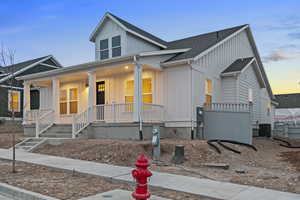 View of front of property with board and batten siding, a shingled roof, and covered porch