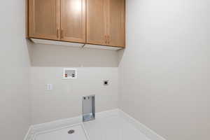 Laundry area with washer hookup, cabinet space, hookup for an electric dryer, and light flooring