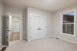 Unfurnished bedroom with light carpet and a closet