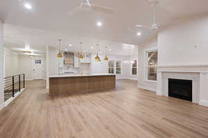Kitchen featuring open floor plan, a large island, a chandelier, a ceiling fan, and a fireplace