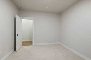 Unfurnished room with light colored carpet and baseboards