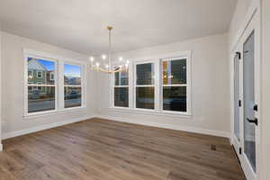 Unfurnished dining area featuring a chandelier and dark wood-style floors