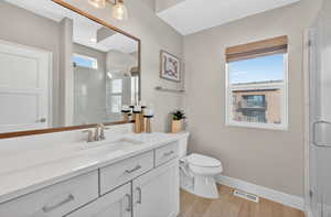 Bathroom featuring a marble finish shower, vanity, and light wood-type flooring