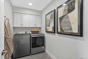 Laundry room with separate washer and dryer, cabinet space, and light tile patterned floors