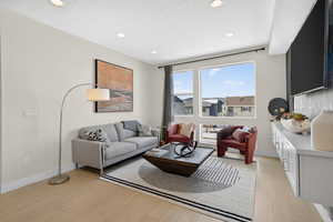 Living area featuring light wood-type flooring, recessed lighting, and a textured ceiling