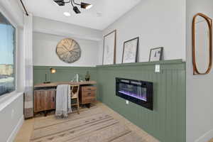 Office space with a glass covered fireplace, a wainscoted wall, and wood finished floors