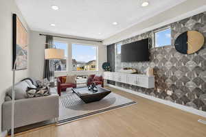 Living room featuring an accent wall, light wood-type flooring, recessed lighting, and a textured ceiling
