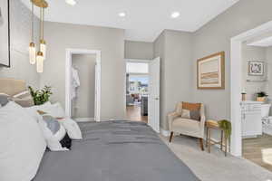 Bedroom featuring ensuite bathroom, light colored carpet, recessed lighting, and light wood-style floors
