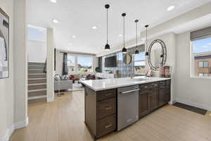 Kitchen with open floor plan, light wood-type flooring, dark wood finish cabinets, a peninsula, and a textured ceiling