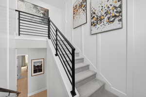 Stairway with wood finished floors and a decorative wall